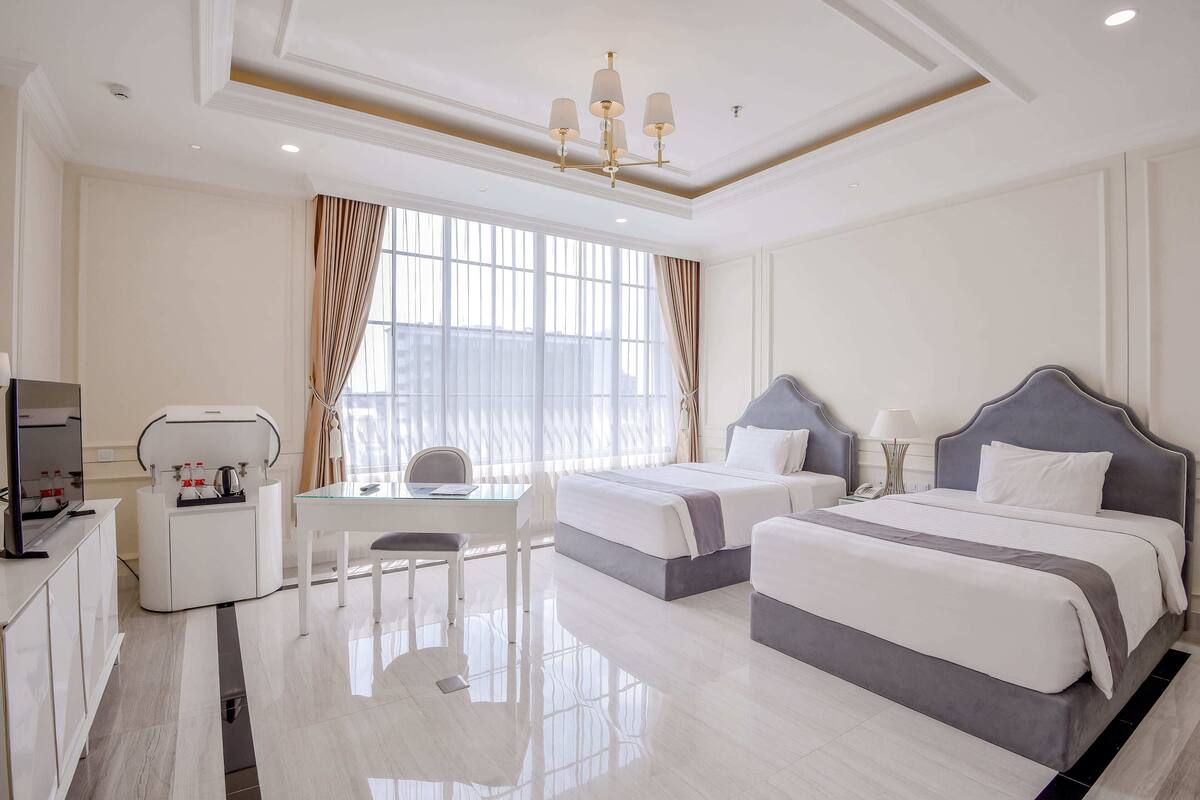 Une chambre d’hôtel avec deux lits, un bureau, une chaise, une télévision et un mini-bar.
