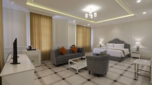 Relax in a stylish room with a large bed, sofa, and armchair, plus a desk and flat-screen TV.
