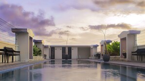 A swimming pool with a view of the sky and buildings in the background. - Grand Senyum Hotel (Yogyakarta)