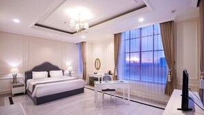 A modern hotel room with a large bed, a desk, and a TV. - Grand Senyum Hotel (Yogyakarta)