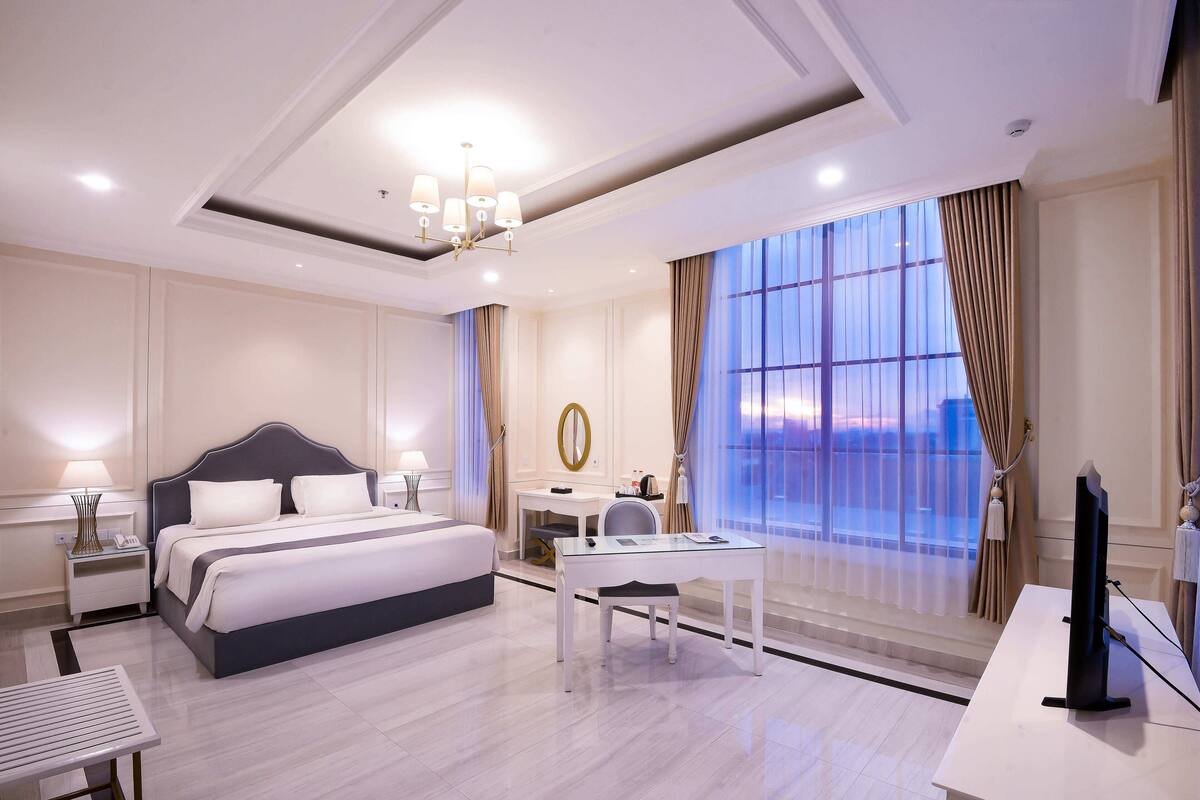 Une chambre d’hôtel moderne avec un grand lit, un bureau et une télévision.