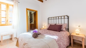 Une chambre à coucher comprenant un lit, des tables de chevet, un banc en bois et une armoire.