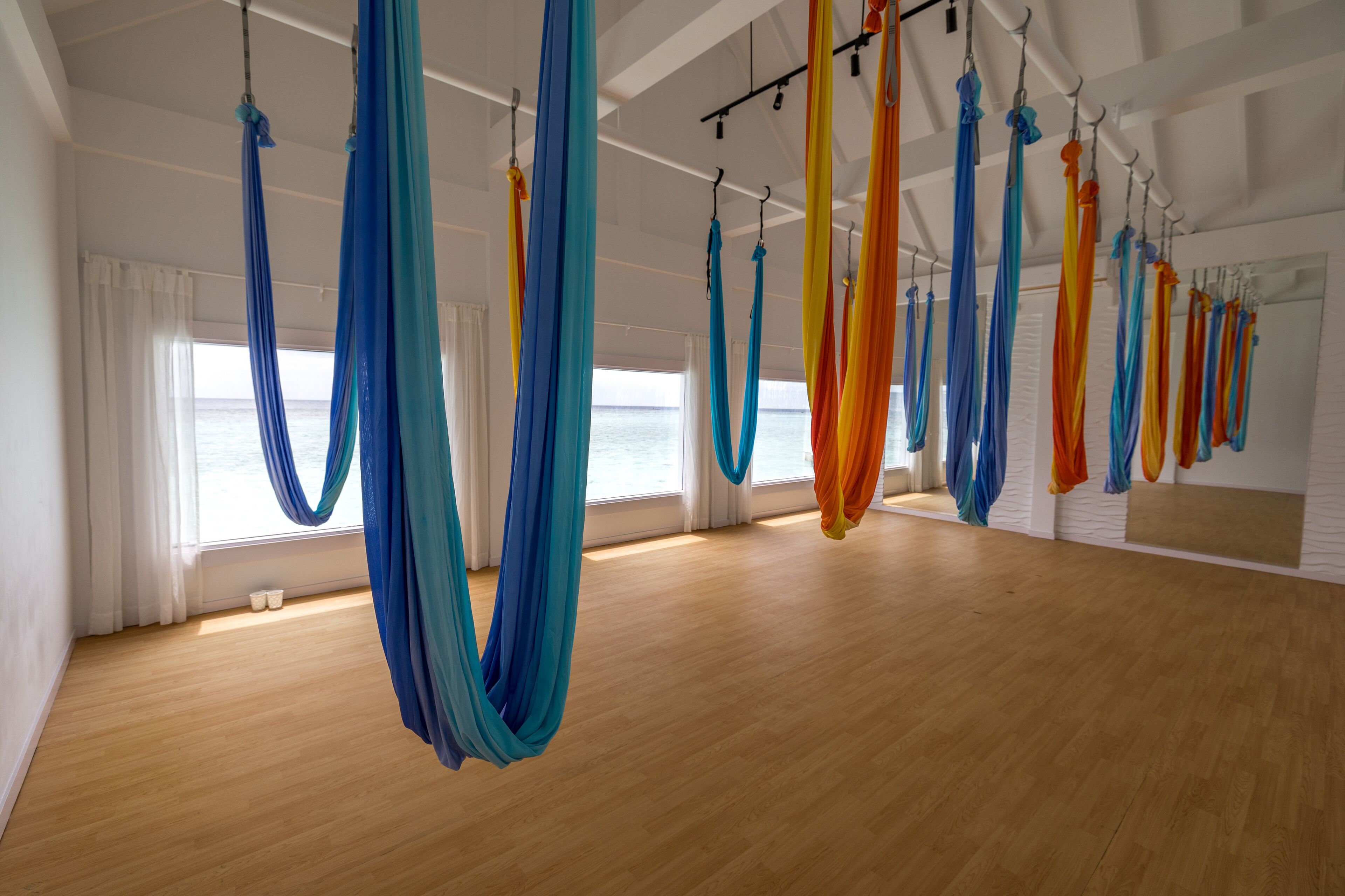 A spacious room with wooden flooring and large windows.