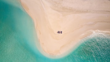 Eine Vogelperspektive zeigt einen Strand mit einer schmalen Sandfläche, die zwei Wassermassen voneinander trennt.