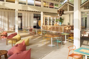 A spacious indoor area with multiple seating arrangements, a bar area, and large windows allowing natural light.
