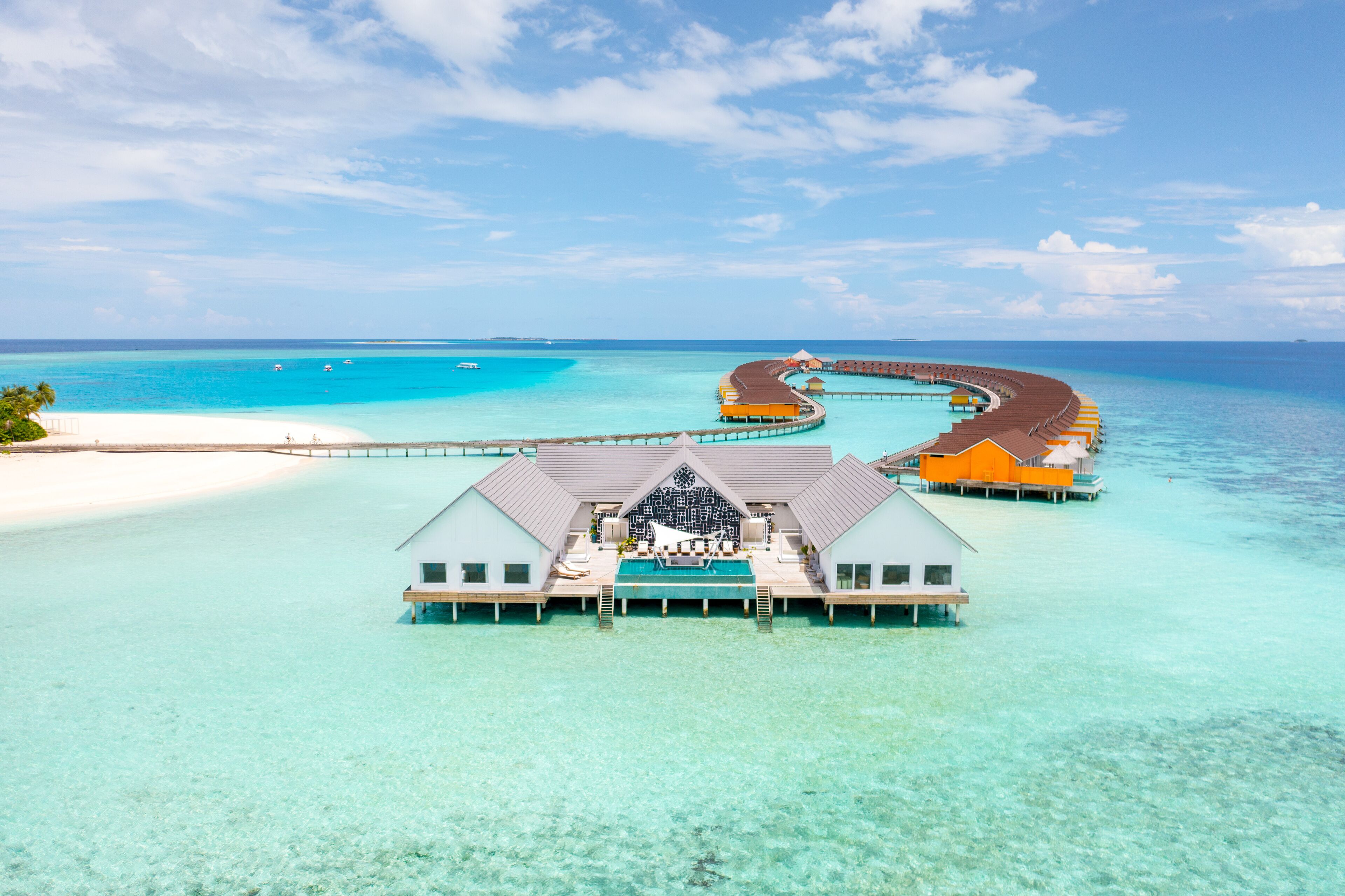 An overwater bungalow with a pool, connected by a curving walkway to other bungalows.