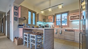 Una cucina moderna con mobili in legno, un'isola centrale con sgabelli da bar, un forno a microonde e un frigorifero.