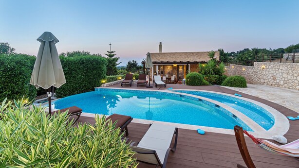 Una piscina con lettini e un piccolo edificio con tetto in tegole.