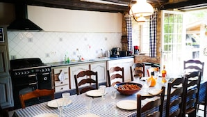 A dining area with a checkered tablecloth, wooden chairs, and a stone backsplash.