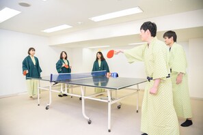 Ein Tischtennis-Tisch in einem Raum mit weißen Wänden und Deckenleuchten.