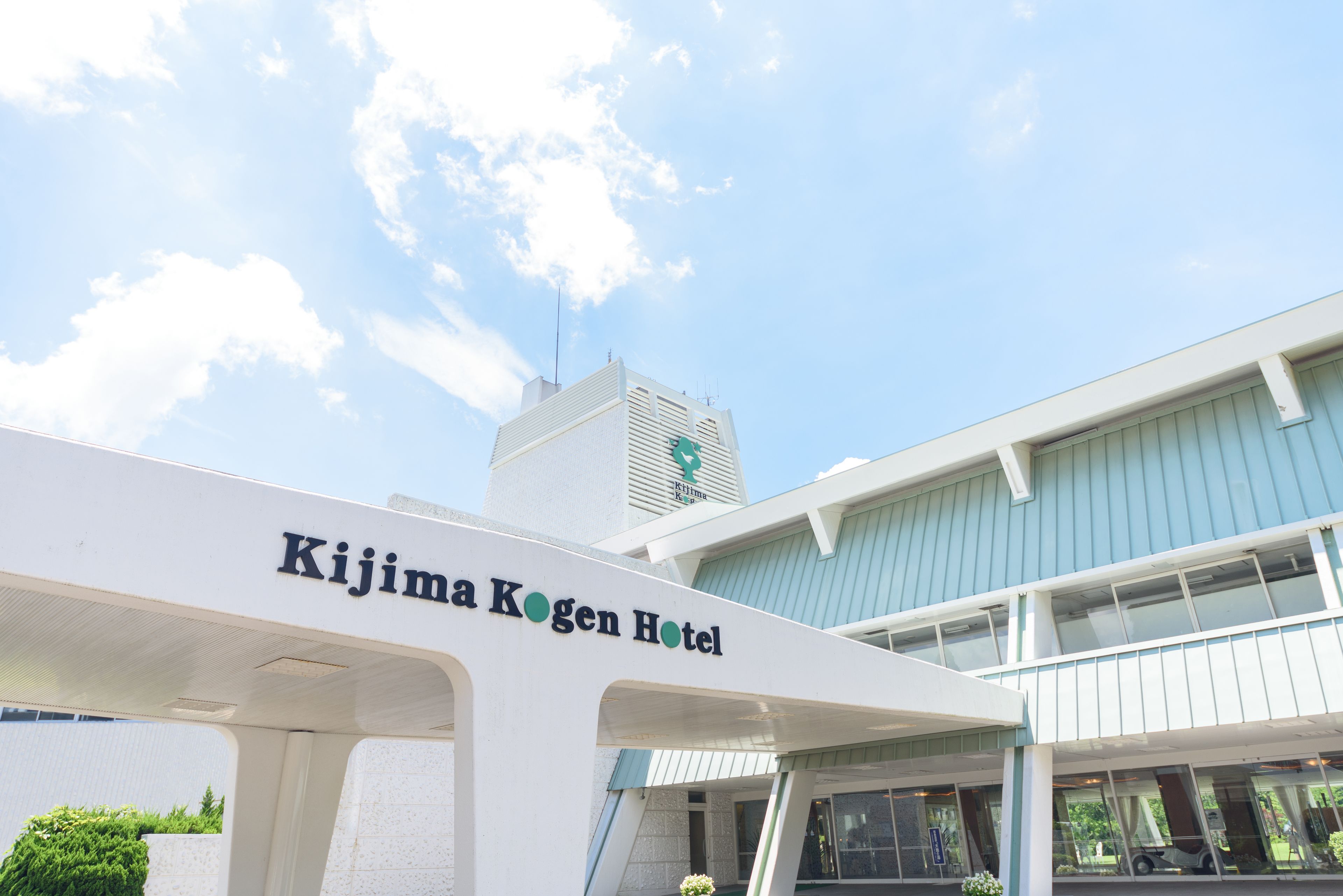 The exterior of the Kijima Kogen Hotel with a clear sky and a modern building structure.