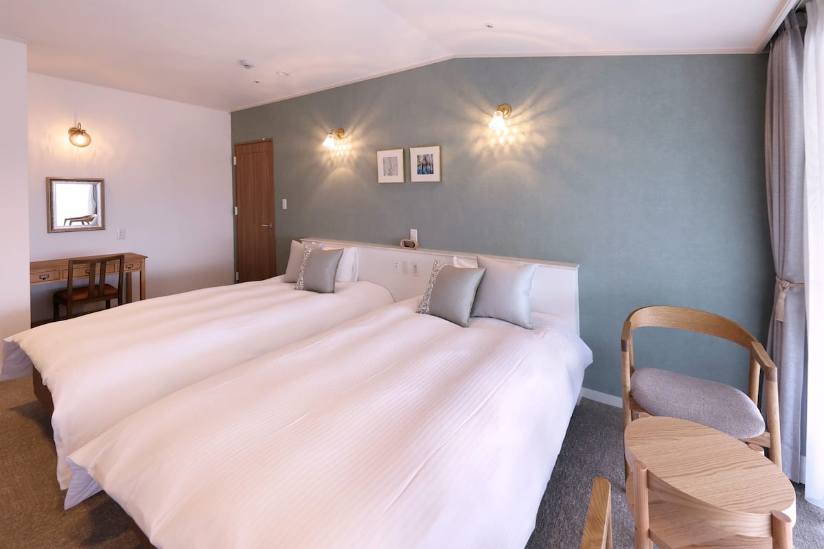 A hotel room with a large bed, a desk, and two wall-mounted lights.