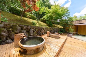 Een traditioneel Japans onsen met houten badkuipen en een achtergrond van een stenen muur.