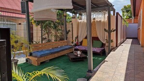 A covered outdoor seating area with a bench, cushions, and a table. - The Saint-louis River villa Cattleya  (La Rivière Saint-Louis)