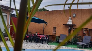 A swimming pool with a tiled deck, a Buddha statue, and outdoor seating with umbrellas. - The Saint-louis River villa Cattleya  (La Rivière Saint-Louis)