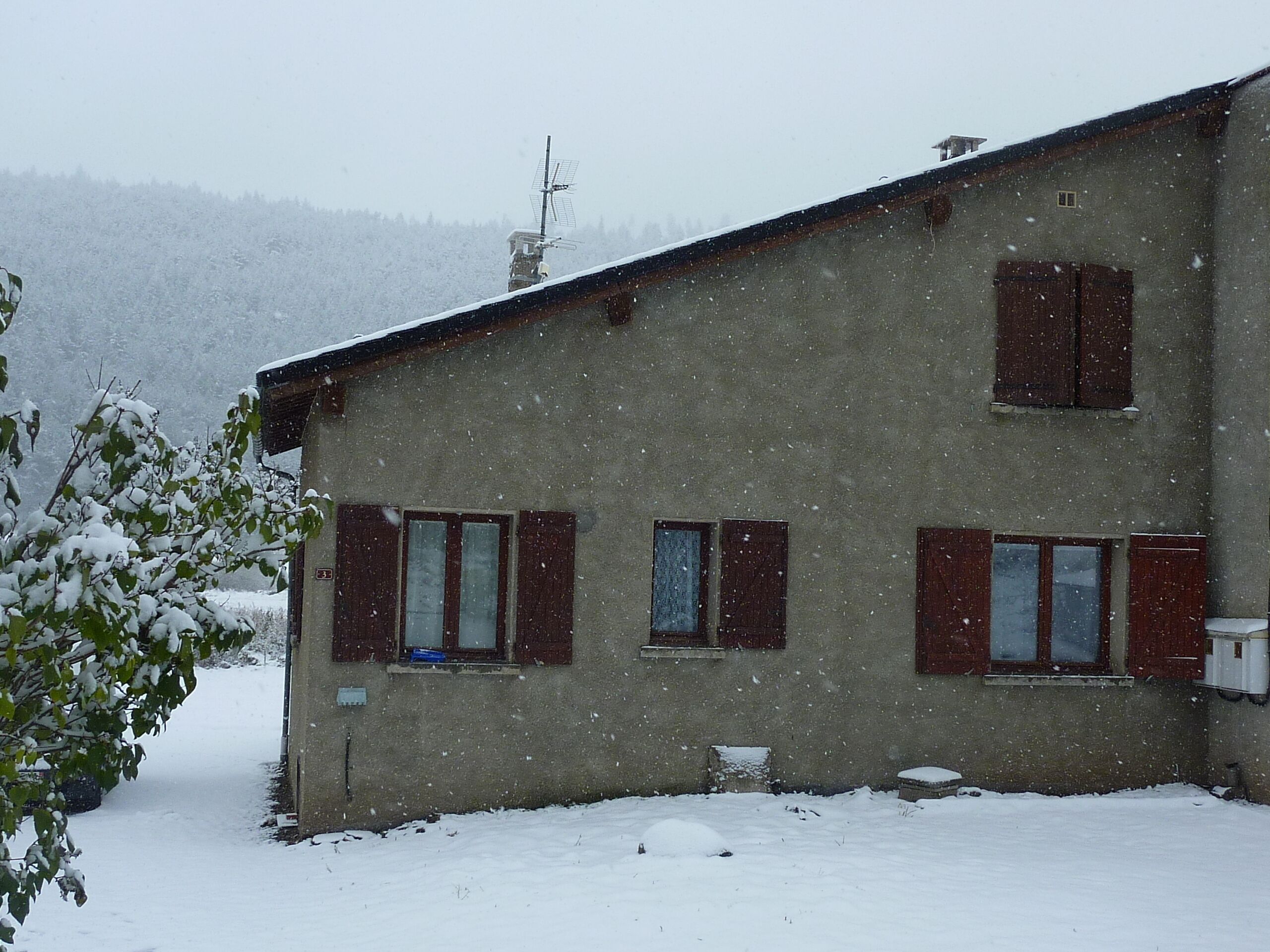 A two-story building with a sloped roof and multiple windows, surrounded by snow.
