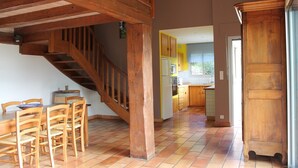 A spacious kitchen with wooden cabinets, a dining area with a table and chairs, and a staircase leading to an upper level.