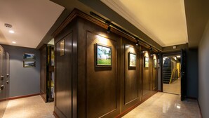 A hallway with wooden paneling, framed pictures, and a staircase in the background. - Little Charm Hanoi Hostel (Hanoi)