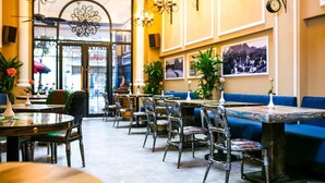 A restaurant interior with round tables, chairs, and blue upholstered seating. - Little Charm Hanoi Hostel (Hanoi)