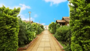 A pathway leading to a building surrounded by lush greenery. - Sunny's World (Paud)