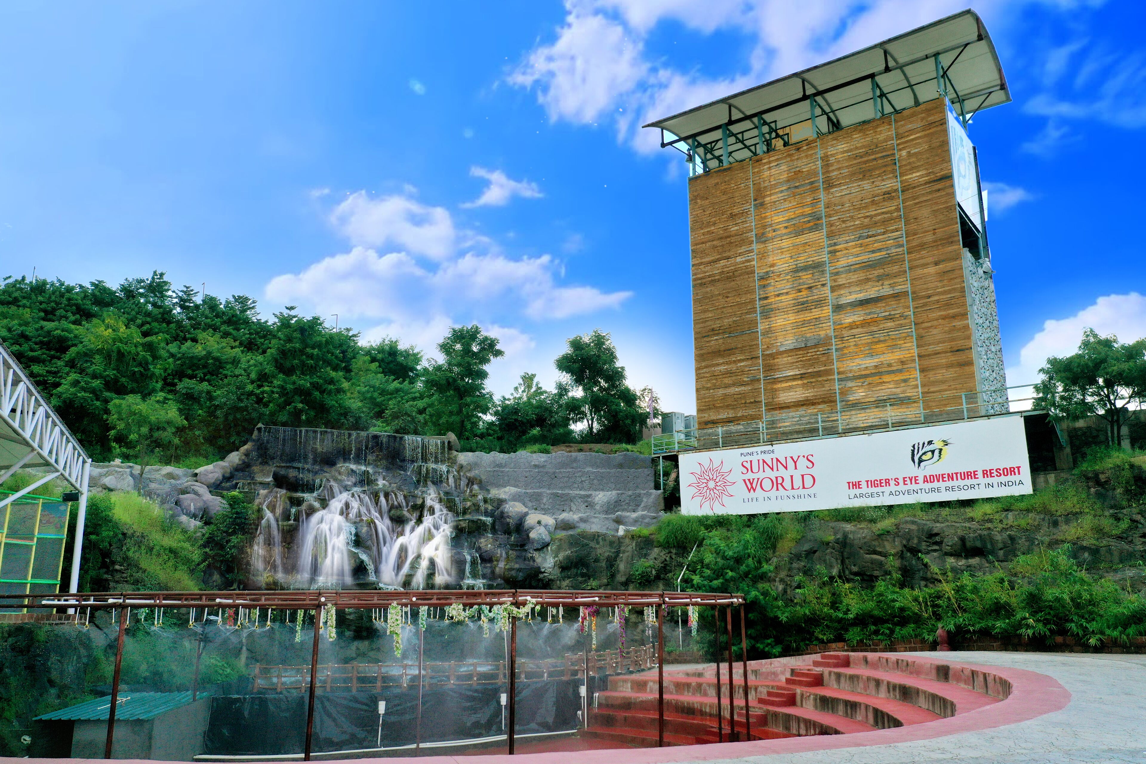 Una cascada, un área de observación con paredes de vidrio y un gran letrero de Sunny's World Tiger's Eye Adventure Resort.