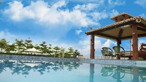 A clear pool with a wooden gazebo and chairs, surrounded by trees and a tiled deck. - Sunny's World (Paud)