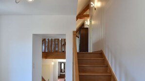 A wooden staircase leading to a second floor with a modern light fixture above.