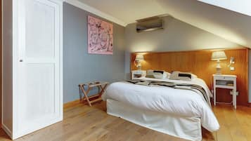 Un dormitorio con cama, dos mesitas de noche, un respiradero en la pared, cabecero de madera y una puerta con panel texturizado.