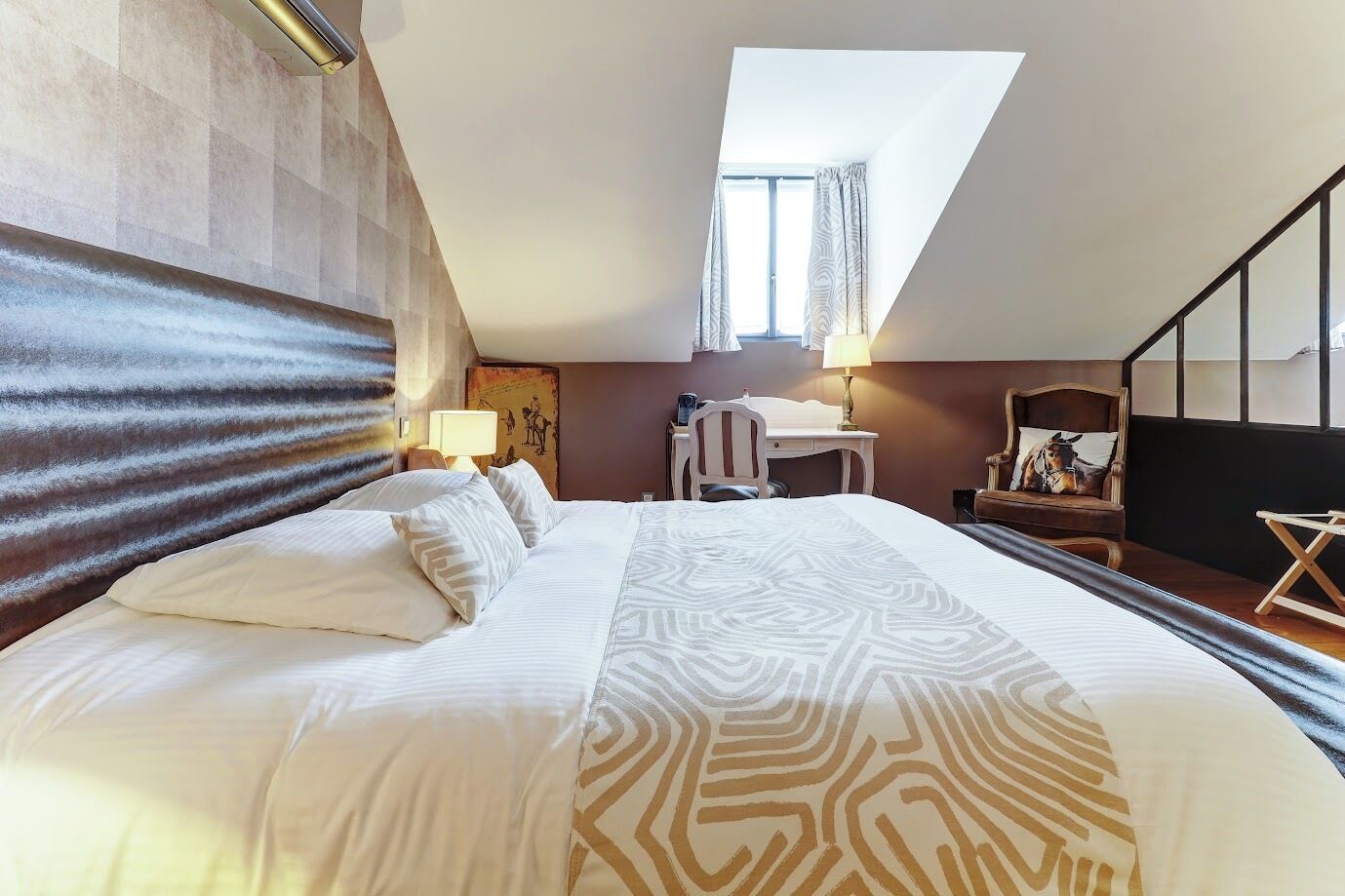Une chambre d’hôtel avec un grand lit, un bureau, une chaise, une lampe et une statue de cheval.