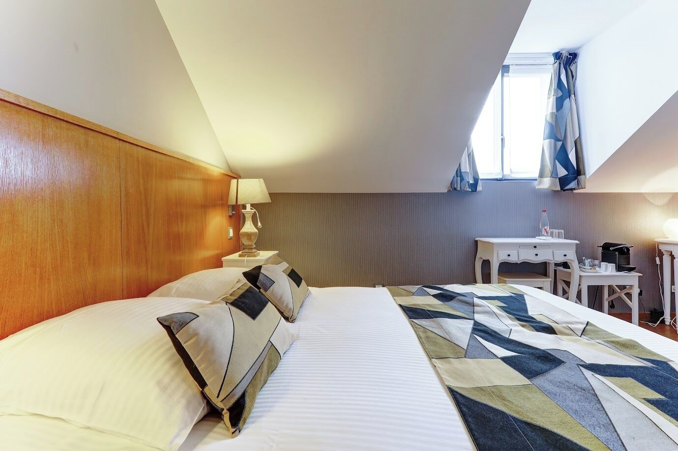 Una habitación de hotel con cama, escritorio, lámpara y ventana.