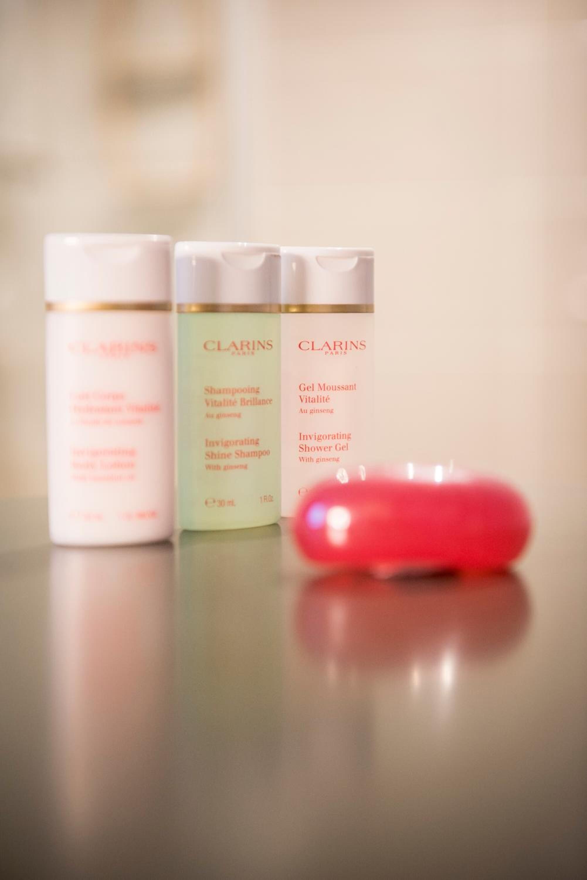 Drie Clarins Paris huidverzorgingsproducten op een reflecterend oppervlak.