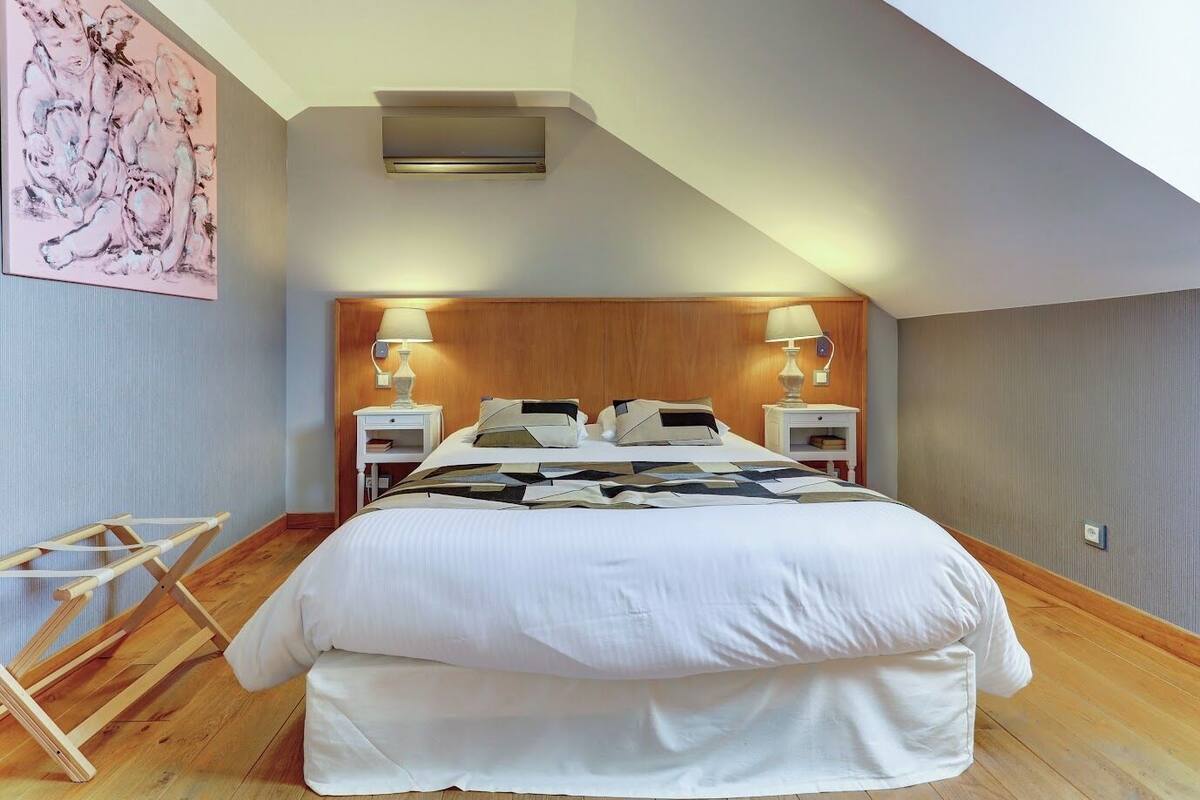 A hotel room with a large bed, two bedside tables with lamps, a wooden headboard, and a ceiling light.