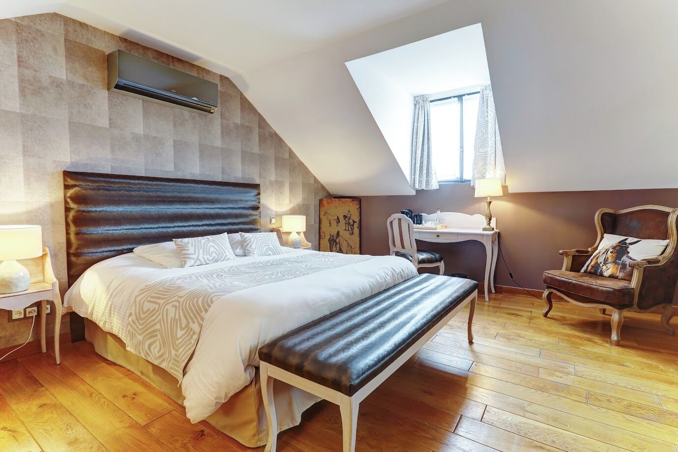 Un dormitorio con cama, escritorio, silla, banco, lámpara y ventana.