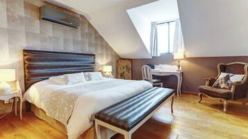 Un dormitorio con cama, escritorio, silla, banco, lámpara y ventana.