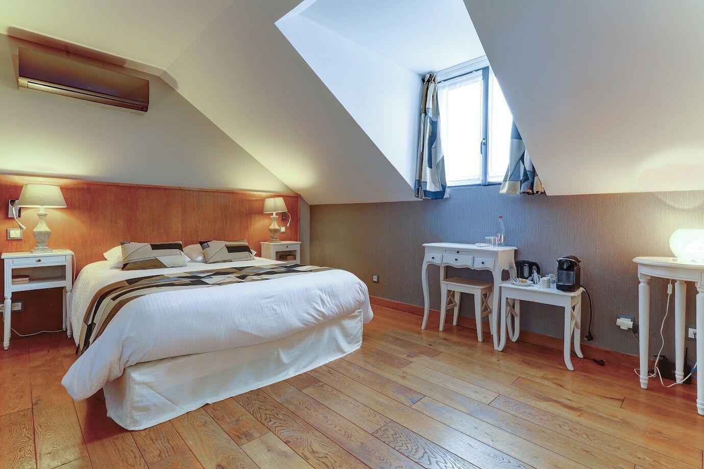 A bedroom with a large bed, a desk, a chair, a lamp, and a window.