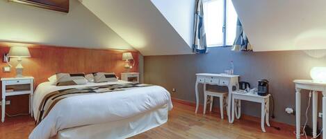 A bedroom with a large bed, a desk, a chair, a lamp, and a window.