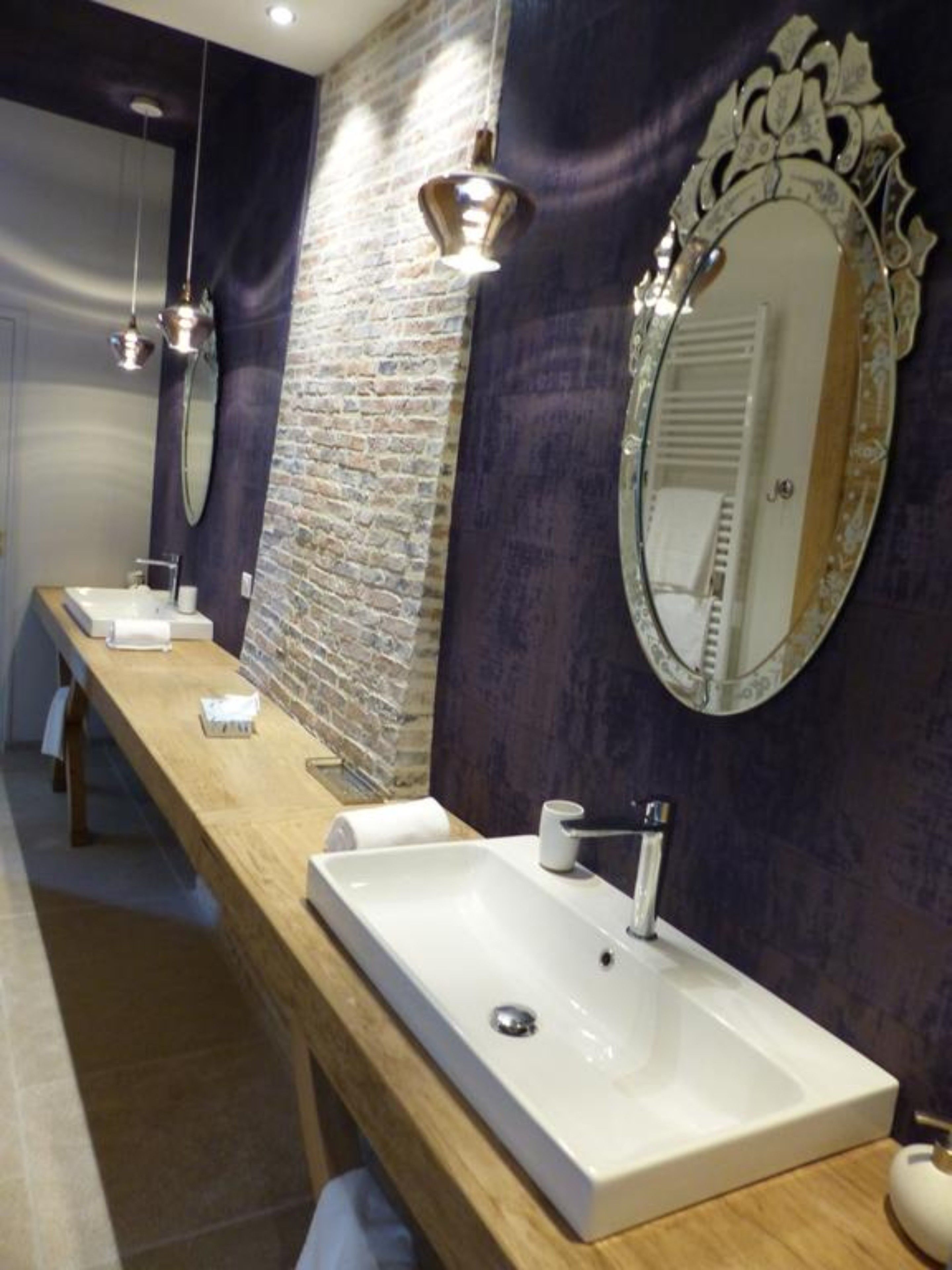 A modern bathroom with a long wooden vanity, a large mirror, and a built-in sink.