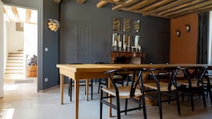 A dining area with a long wooden table and chairs, a buffet counter, and a staircase leading to another room. - La Ferme du Château (Anthenay)