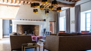 A cozy living room with a fireplace, two sofas, a coffee table, and a chandelier. - La Ferme du Château (Anthenay)