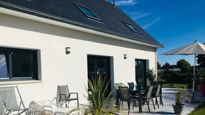 A modern house with a patio area featuring outdoor furniture and a potted plant.