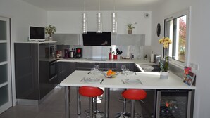 A modern kitchen with a central island, stainless steel appliances, and red bar stools.