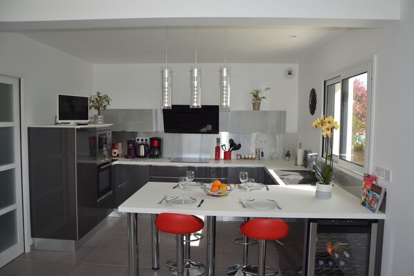 A modern kitchen with a central island, stainless steel appliances, and red bar stools.