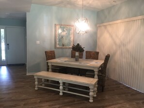 Enjoy meals in this stylish dining area with a round chandelier, a framed painting, and comfortable seating.