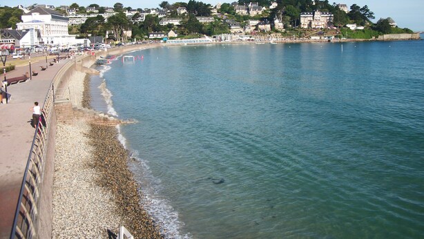 A coastal town with a promenade, buildings, and a beach.