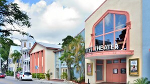 Um teatro com fachada rosa e branca, uma grande entrada em arco e uma placa com a inscrição 