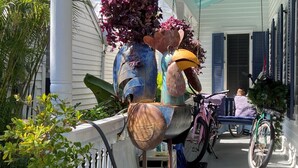Varanda com escultura de metal, bicicletas e árvore de Natal.