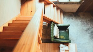 A wooden staircase leading to a room with a green chair and a small table. - Loku.Tainan (Tainan)