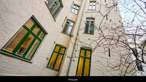 A multi-story building with white walls and green-framed windows. - Apt. Odins Gate (Oslo)