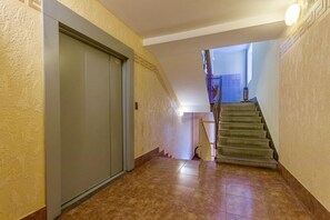 Staircase leads to a spacious area with a decorative patterned wall and a door.