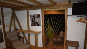 A rustic wooden room with a wooden table, two chairs, a small wooden bench, and a television mounted on the wall. - KAZATIPUNCH - CHARMING BUNGALOW IN TROPICAL GARDEN (st francois)